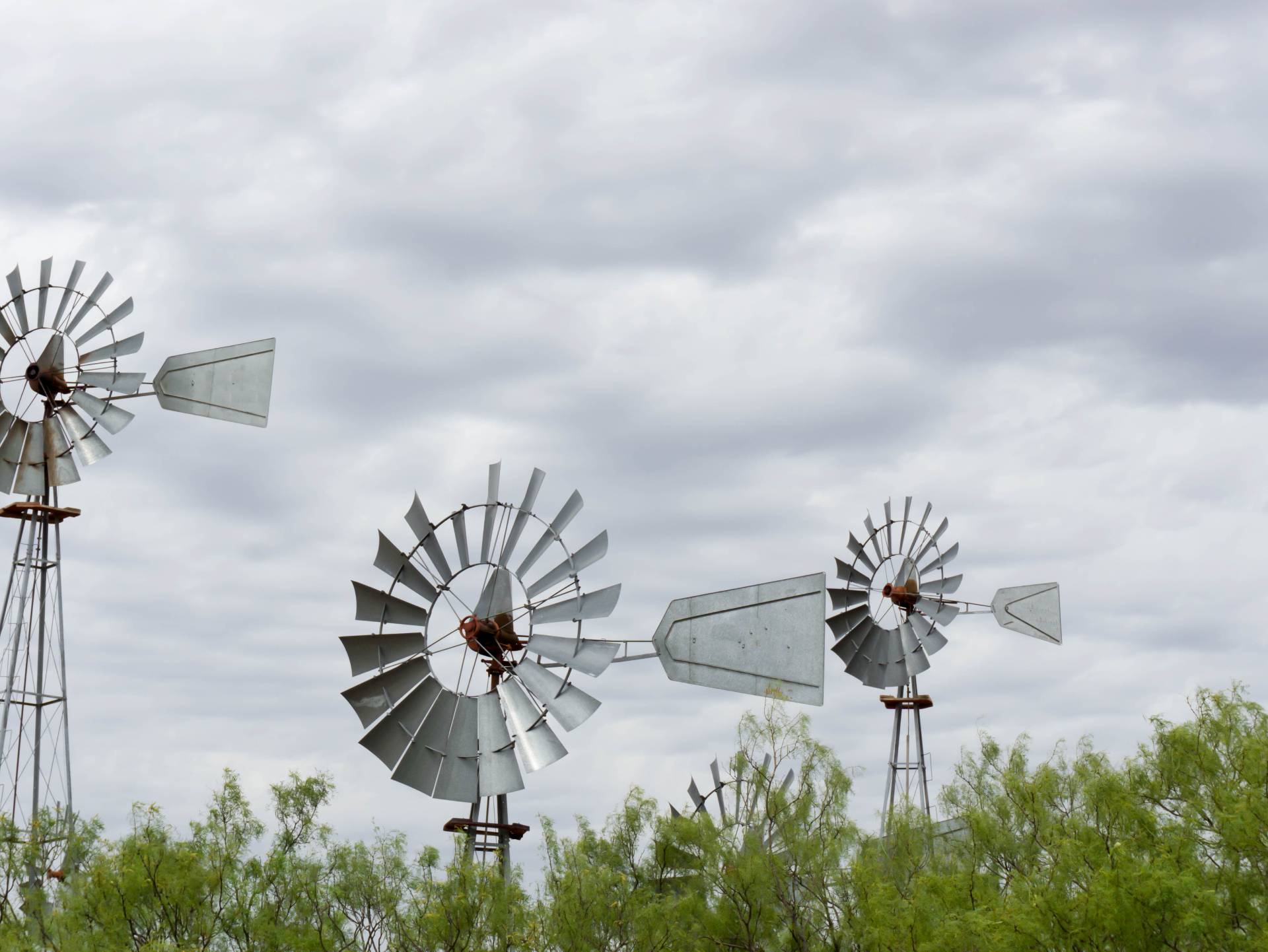 group of four windmills standing tall against a cloudy sky